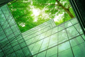 Eco-friendly building in the modern city. Sustainable glass office building with tree for reducing heat and carbon dioxide