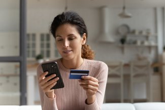 Focused concentrated millennial female using mobile telephone to make easy safe payment online in electronic bank system