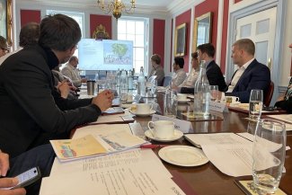  Several individuals gathered at a table in a conference room, participating in a meeting.