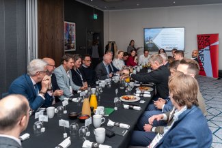 A long table with a group of people sitting together, sharing ideas and dialogue.