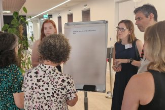 A diverse group of individuals gathered around a whiteboard, discussing ideas and collaborating on a project.