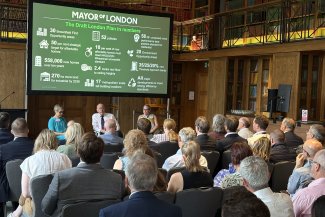 A diverse audience sitting in a room, focused on a presentation projected on a large screen.