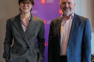 Jenevieve Treadwell and John Dickie in formal suits standing side by side, both smiling and looking towards the camera.