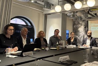 A group of individuals around a table listen to discussion