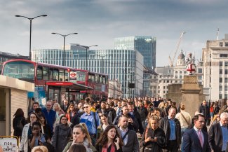 Commuters and red buses crossing London Bridge during rush hour