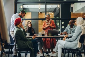 Happy businesspeople smiling cheerfully during a meeting in a creative office. Group of successful business professionals working as a team in a multicultural workplace