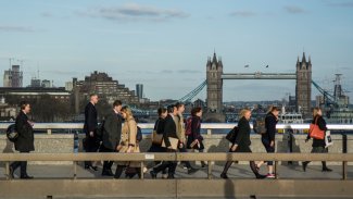 Crowds of office workers walking across London Bridge from the City of London past Tower Bridge in the background