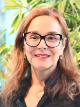 Professor Amanda Broderick smiles to camera. She has auburn hair and wears glasses