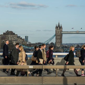 Crowds of office workers walking across London Bridge from the City of London past Tower Bridge in the background