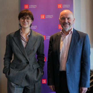 Jenevieve Treadwell and John Dickie in formal suits standing side by side, both smiling and looking towards the camera.