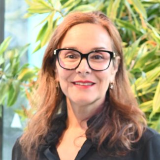 Professor Amanda Broderick smiles to camera. She has auburn hair and wears glasses