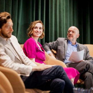 Three individual engaging in discussion on a conference stage