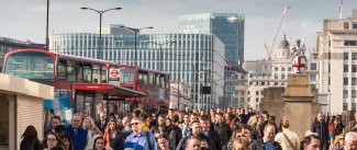 Commuters and red buses crossing London Bridge during rush hour